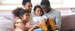 African American family sitting together on couch all smiling