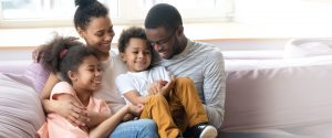African American family sitting together on couch all smiling