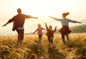 Family running through a field at sunset.